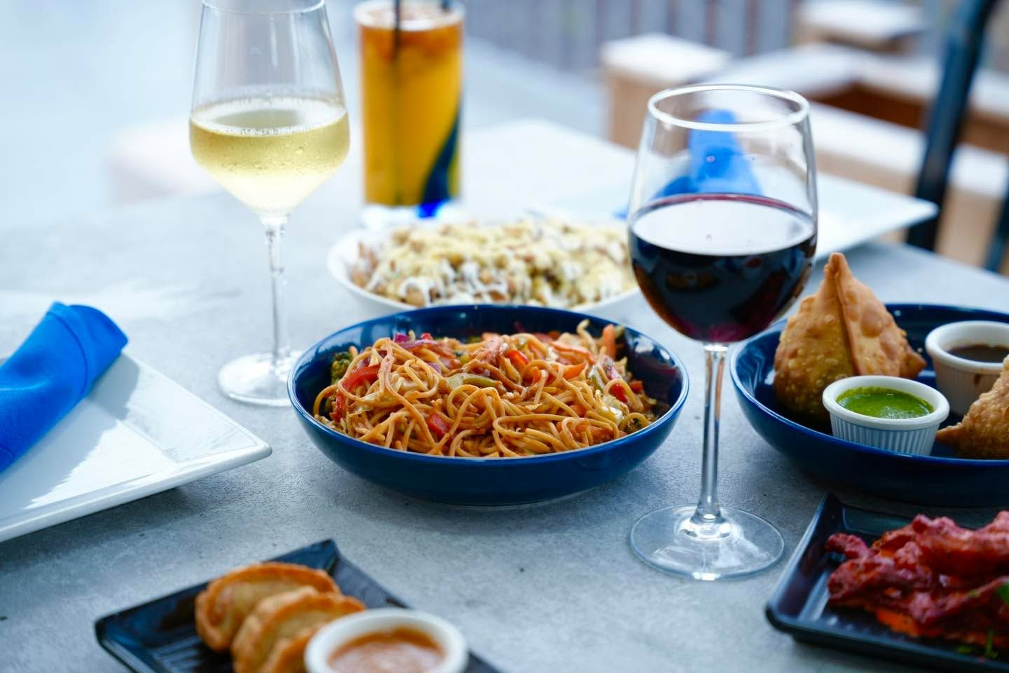 Noodles, samosas and momos with glasses of wine