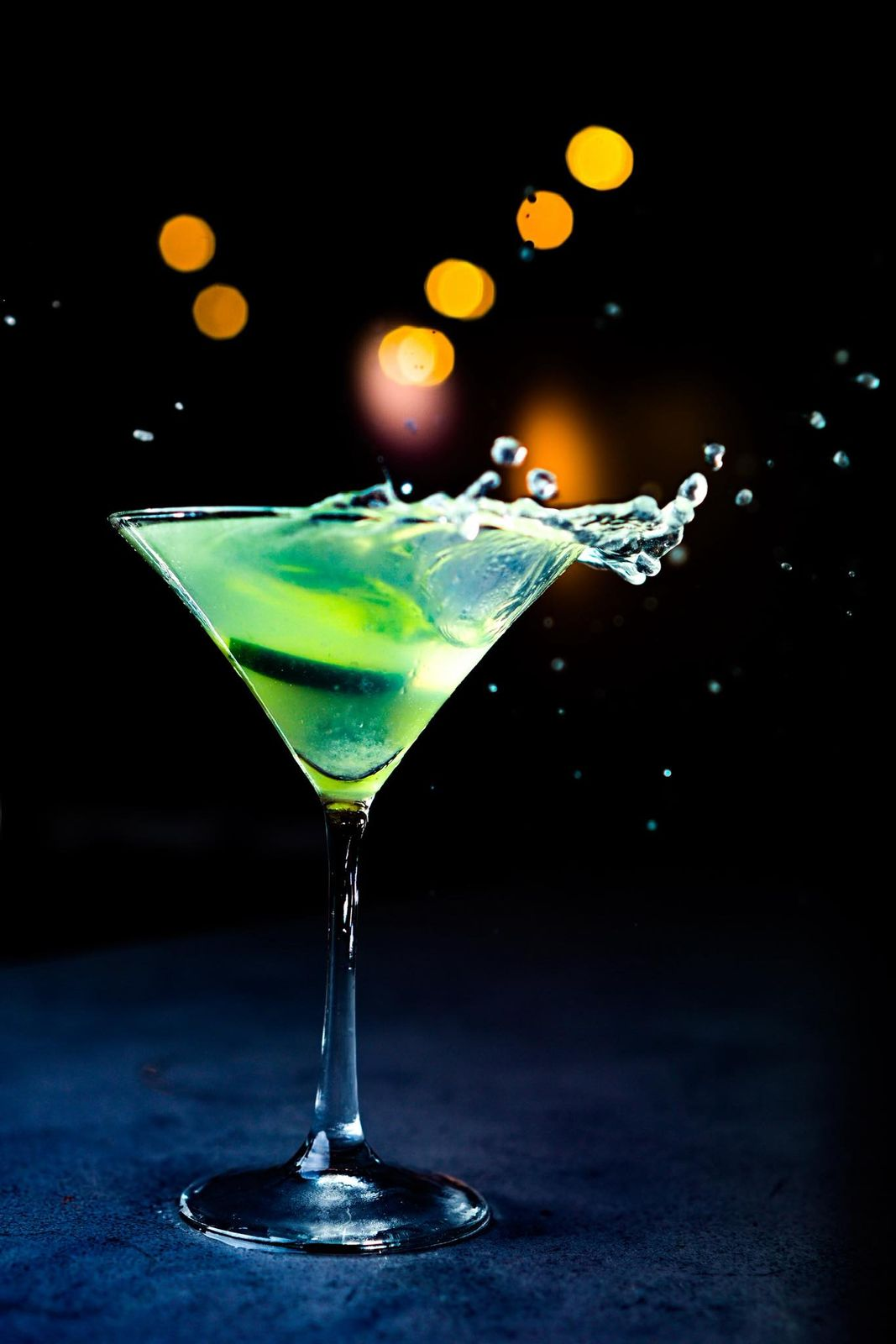 A green cocktail splashing in a martini glass