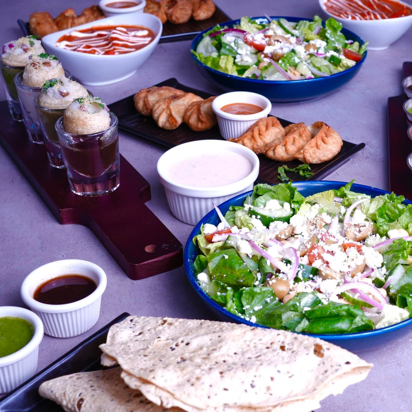 A spread of momos, salads, pani puri and papadum